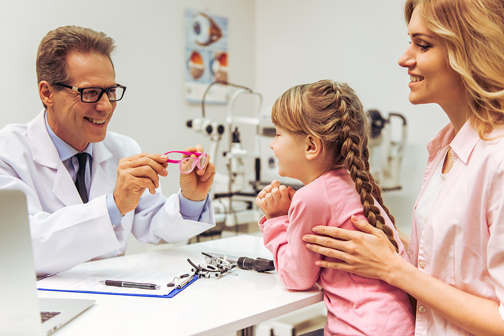 Happy little boy with mother giving a high five to eye doctor